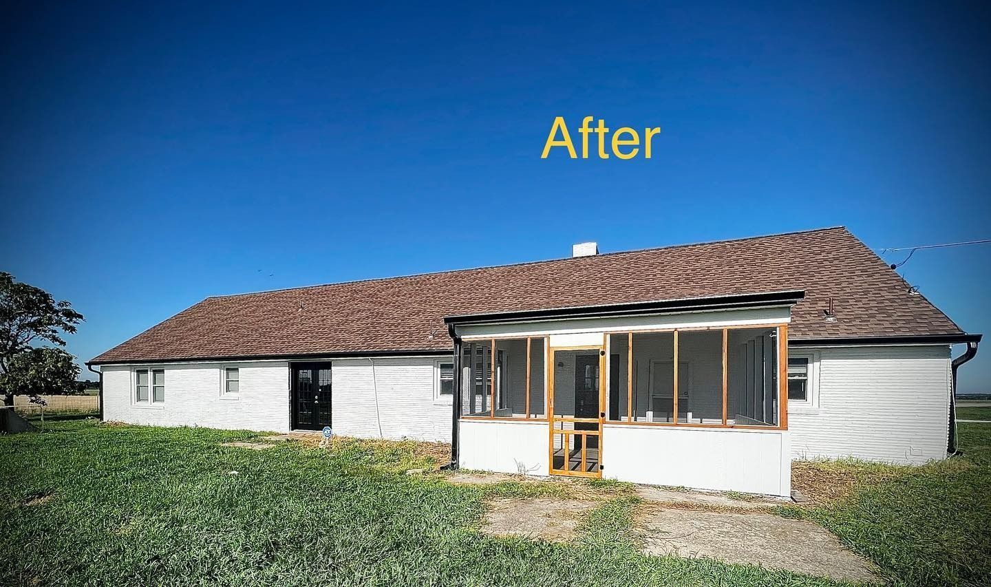 A white house with a screened in porch and a brown roof.