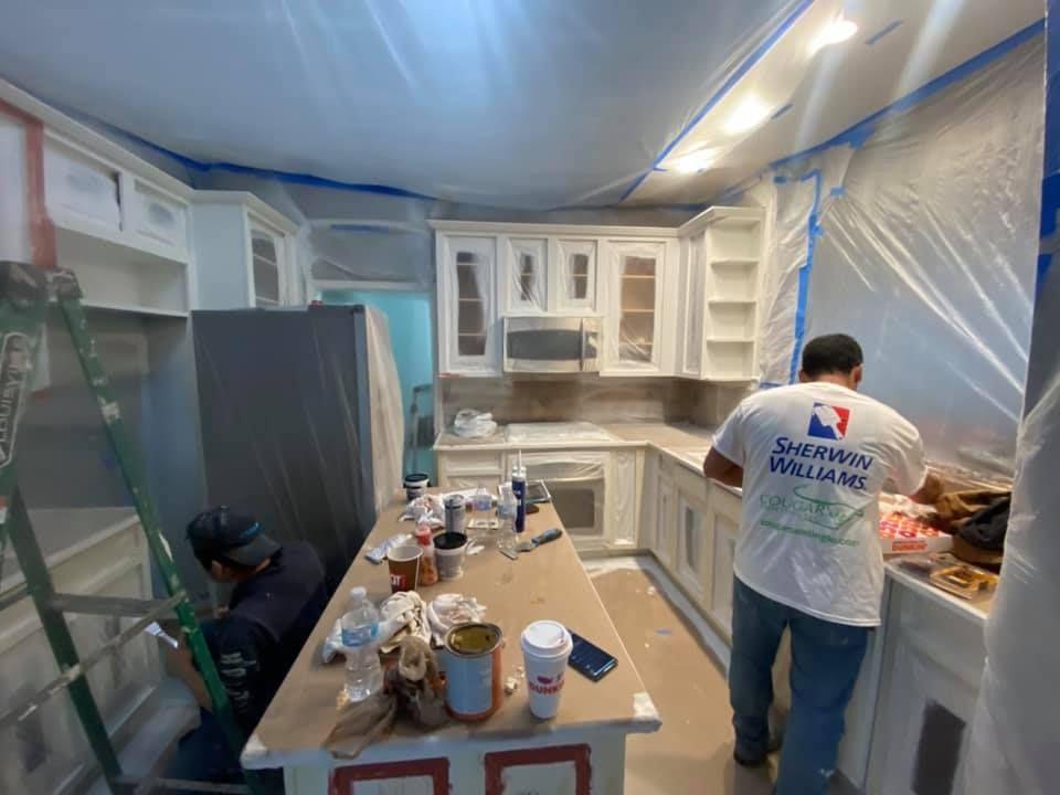 A man in a sherwin williams shirt is painting a kitchen.