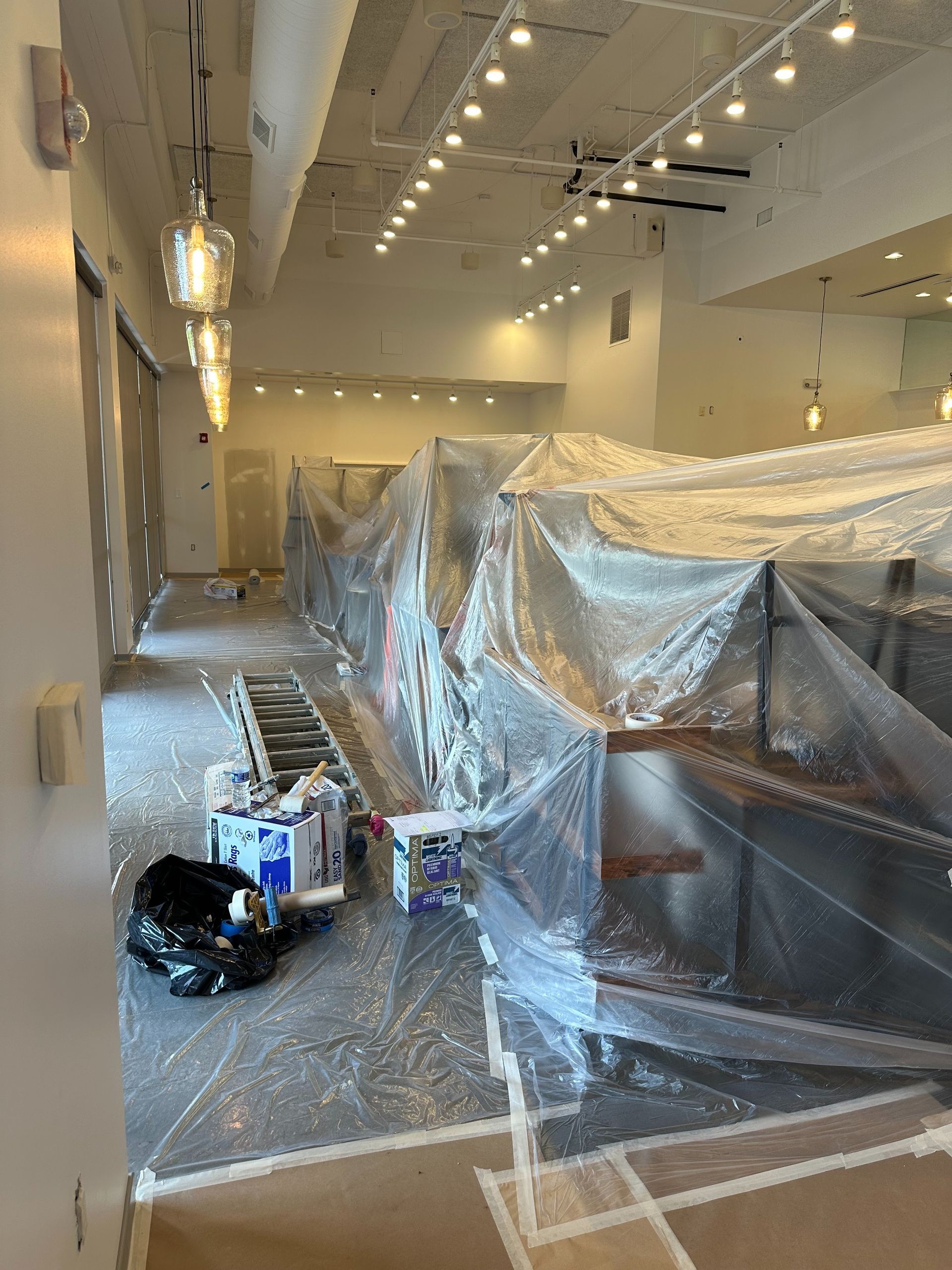 A large room is being painted and covered in plastic.