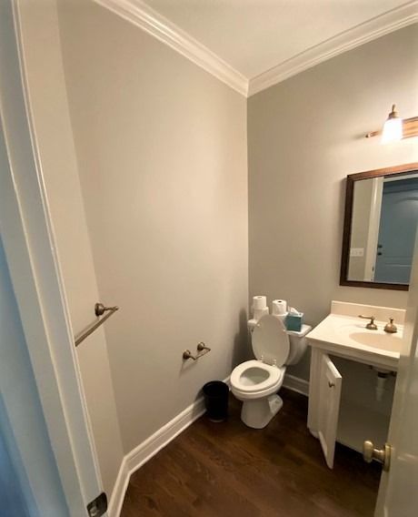 A bathroom with a toilet , sink and mirror.