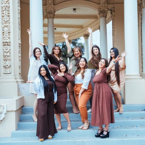 A group of women are posing for a picture on the steps of a building.