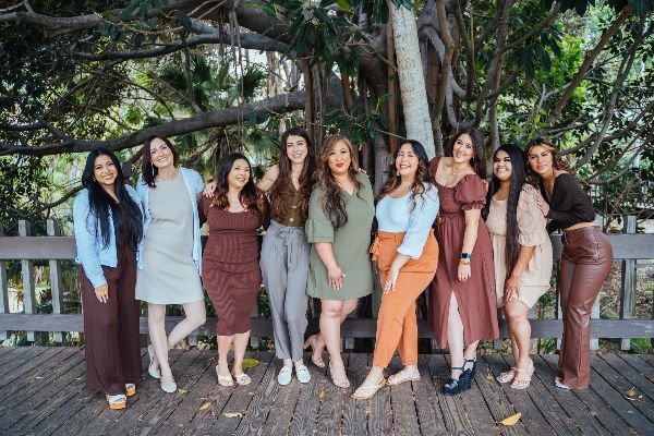 A group of women are posing for a picture in front of a tree.