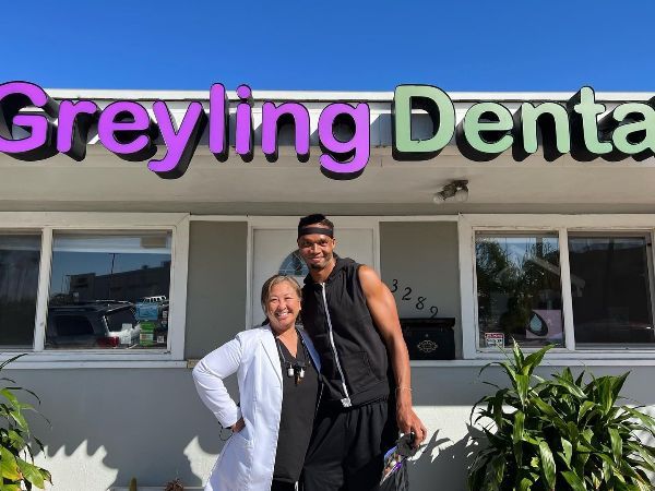 A man and a woman standing in front of a greyling dental office