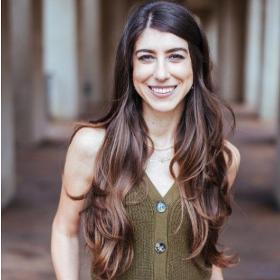 A woman with long hair is smiling for the camera while wearing a green tank top.
