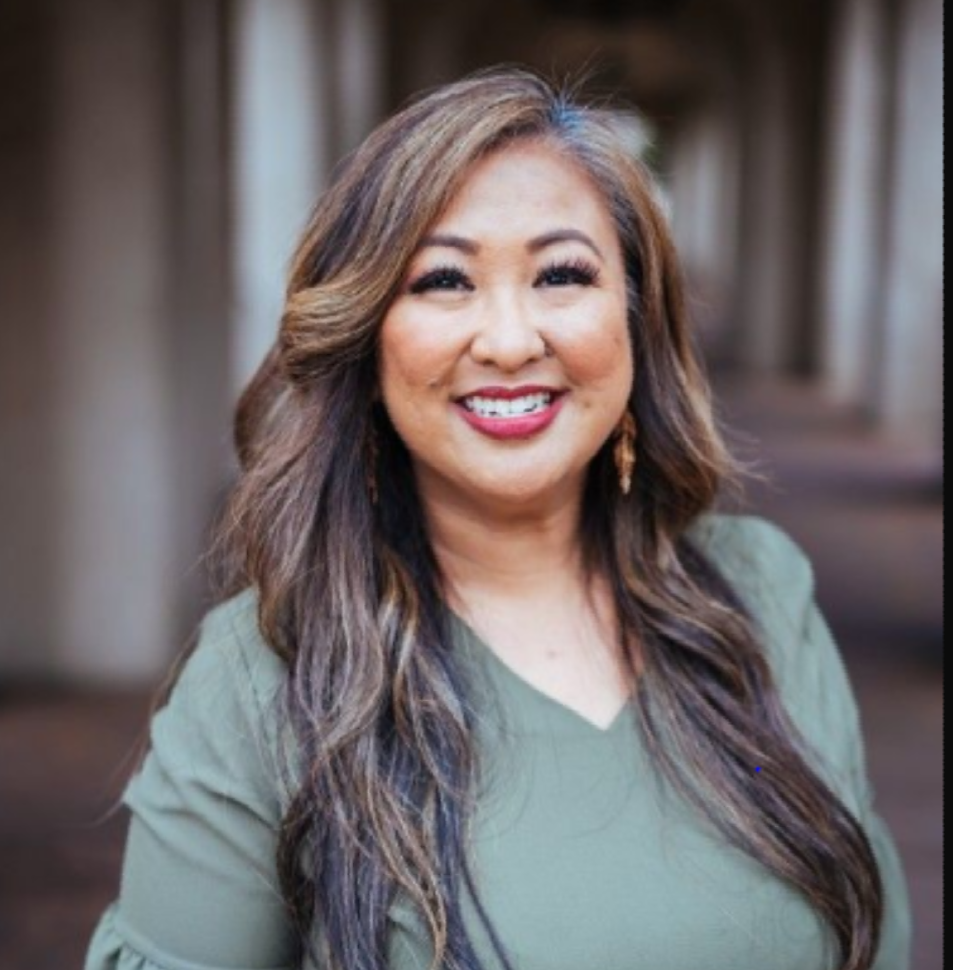 A woman in a green shirt is smiling for the camera.