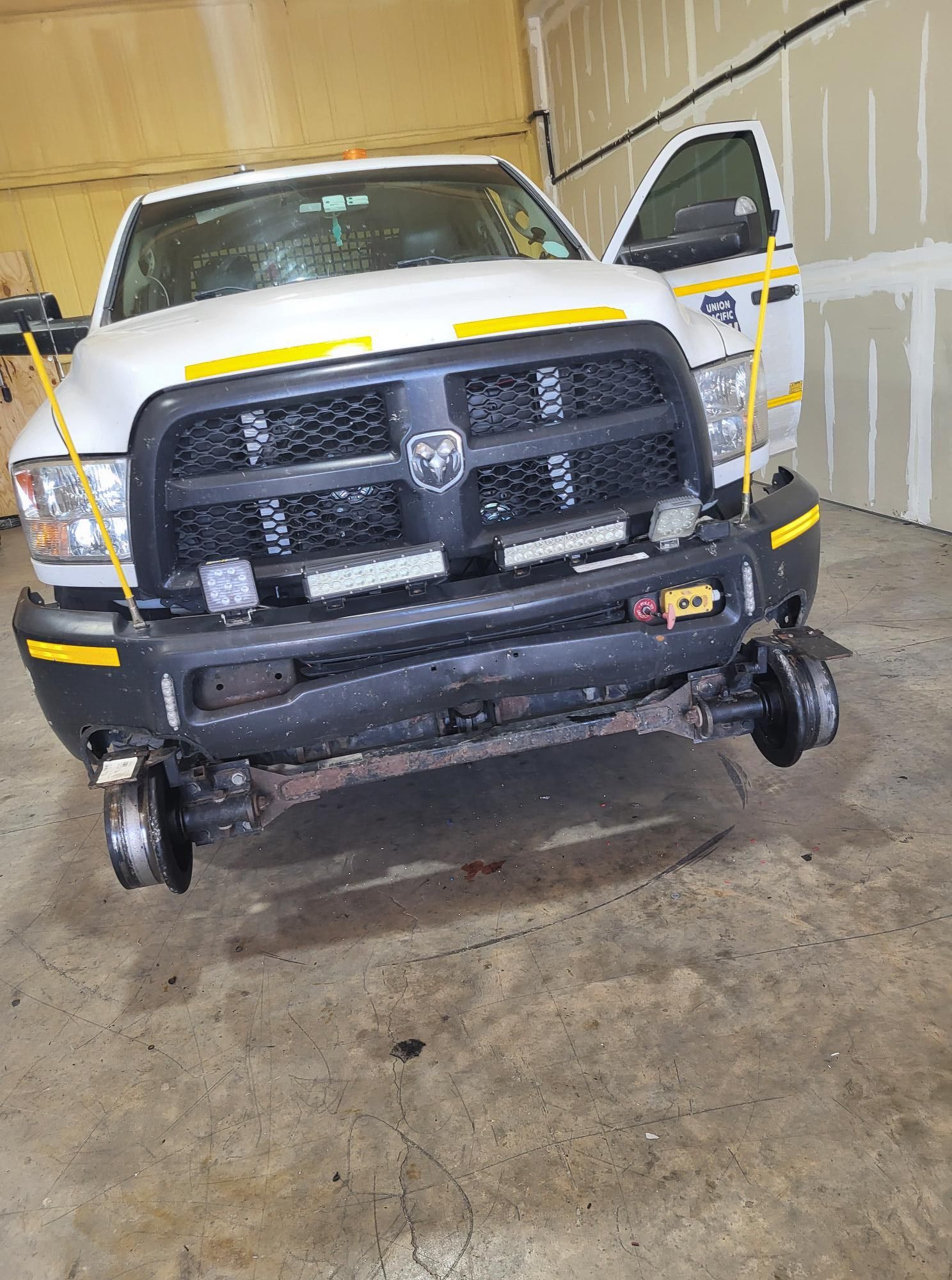 A white truck with wheels on it is parked in a garage.