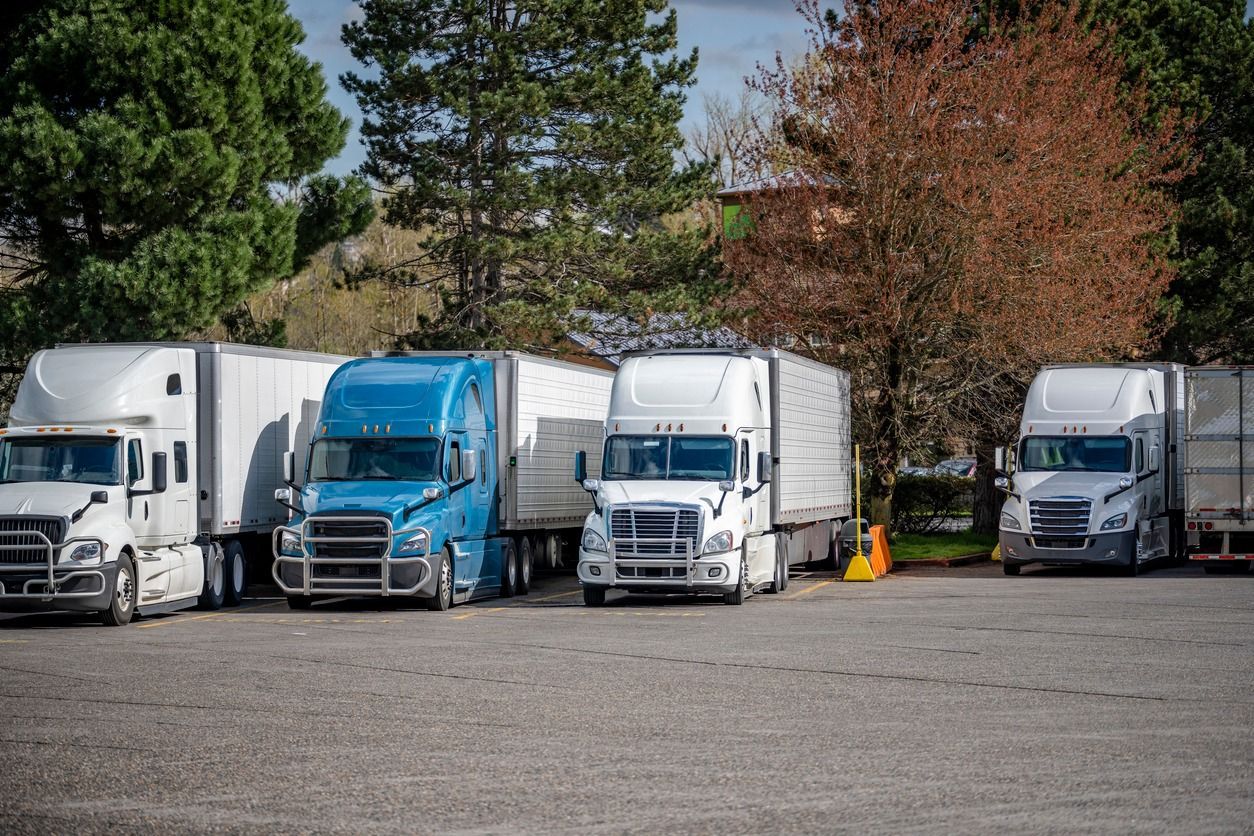 A row of semi trucks are parked in a parking lot.
