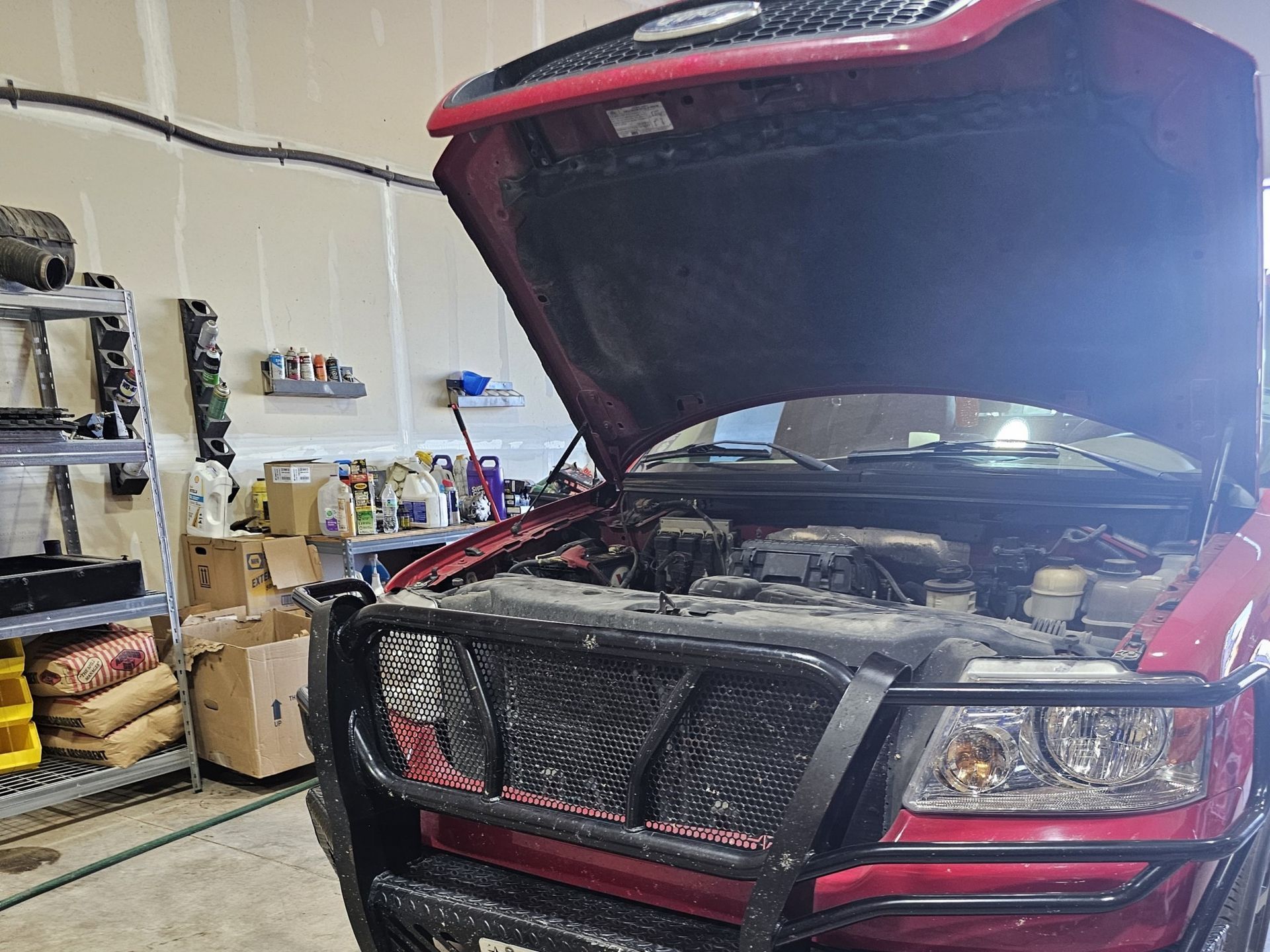 A red truck with the hood up in a garage.