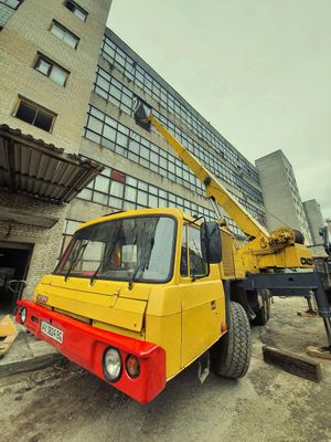 A yellow truck with a red bumper is parked in front of a building.