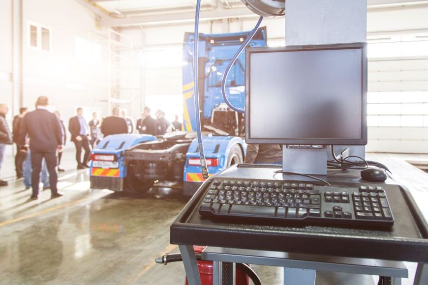 A computer is sitting on a desk in a garage next to a truck.