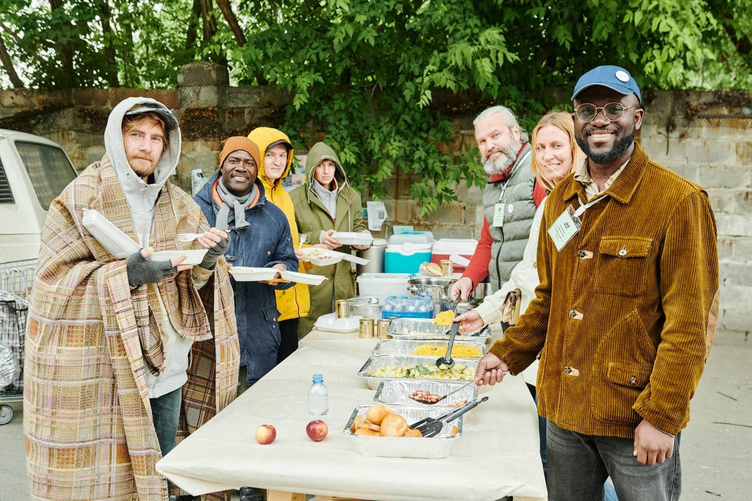 A group of people are standing around a table eating food.