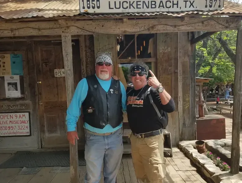 Two men standing in front of a building that says luckenbach tx