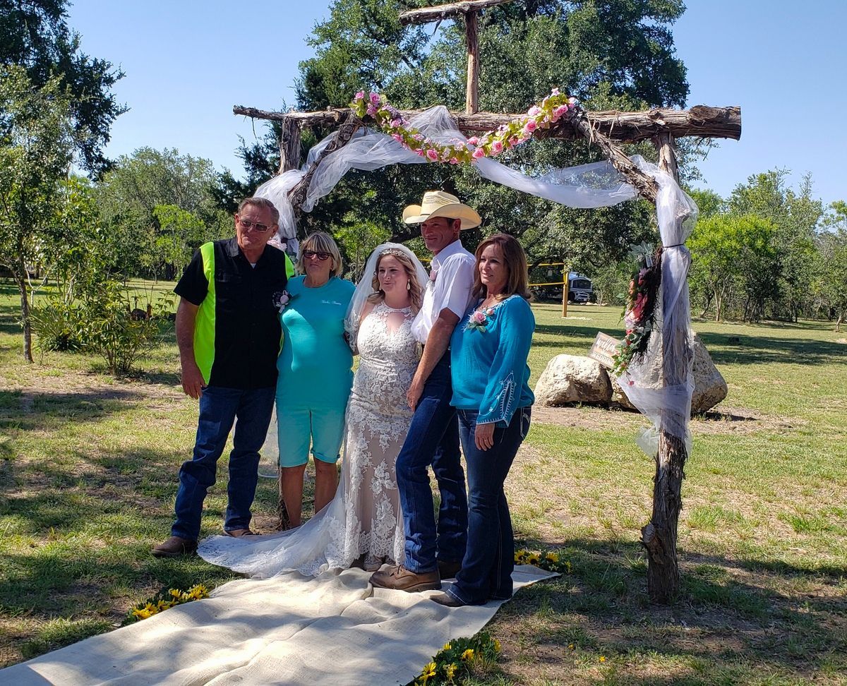A group of people are posing for a picture in front of a wooden arch.