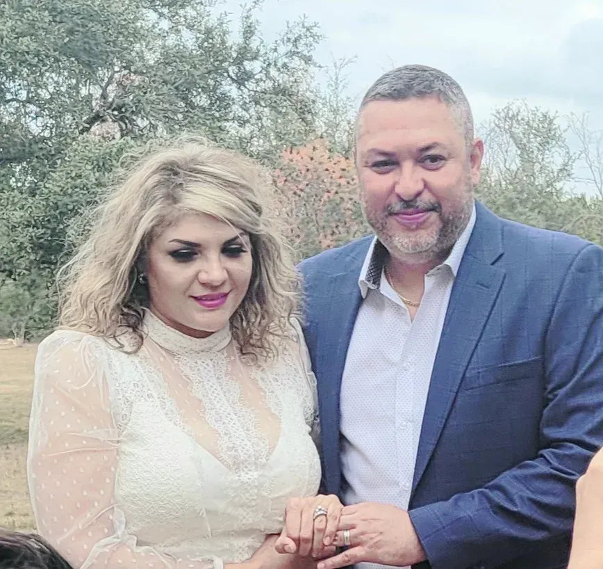A man in a suit and a woman in a white dress are posing for a picture.