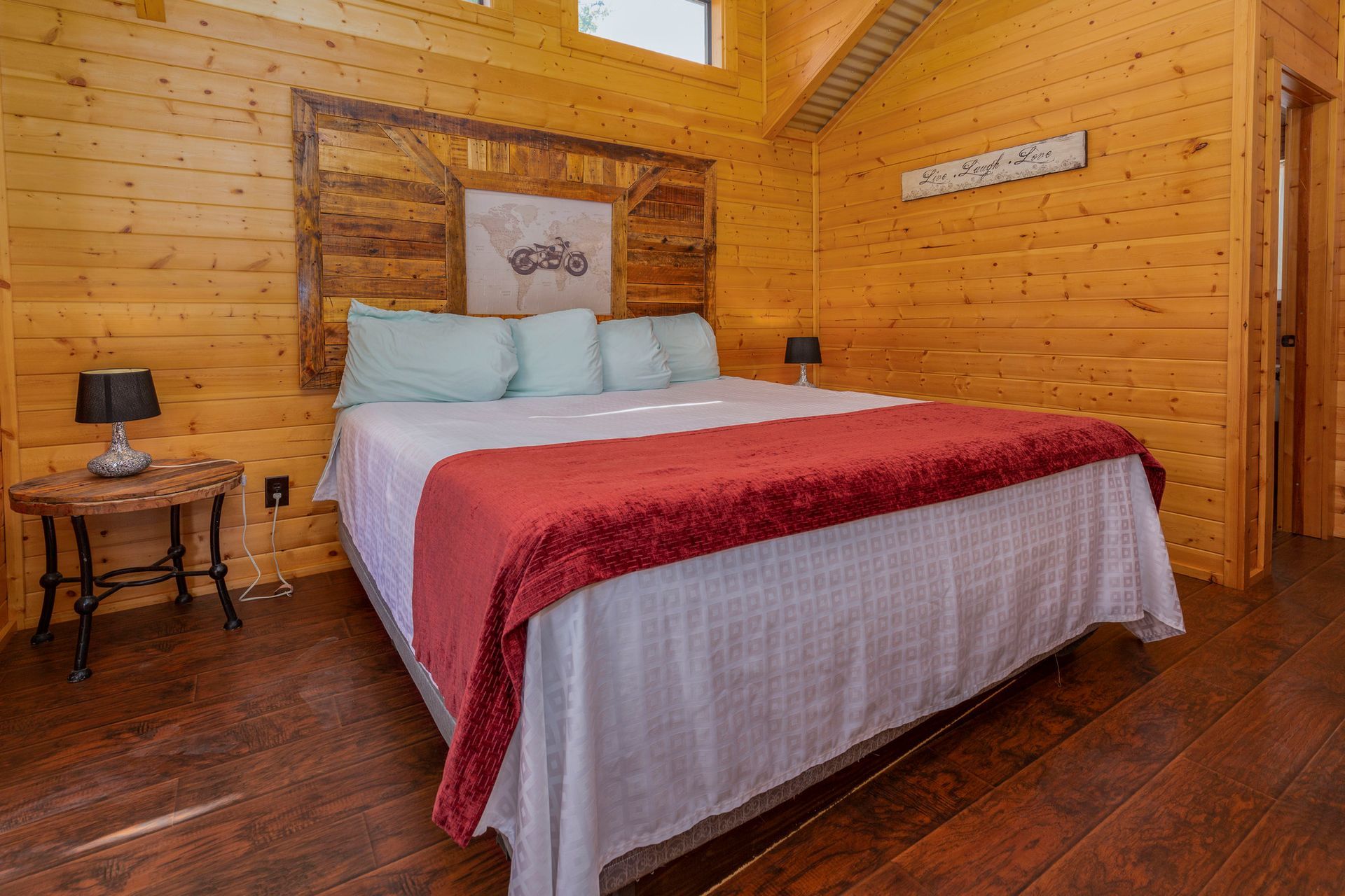 A bedroom in a log cabin with a king size bed and a wooden headboard.