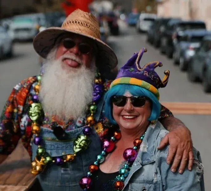 A man with a beard and a woman with blue hair are posing for a picture