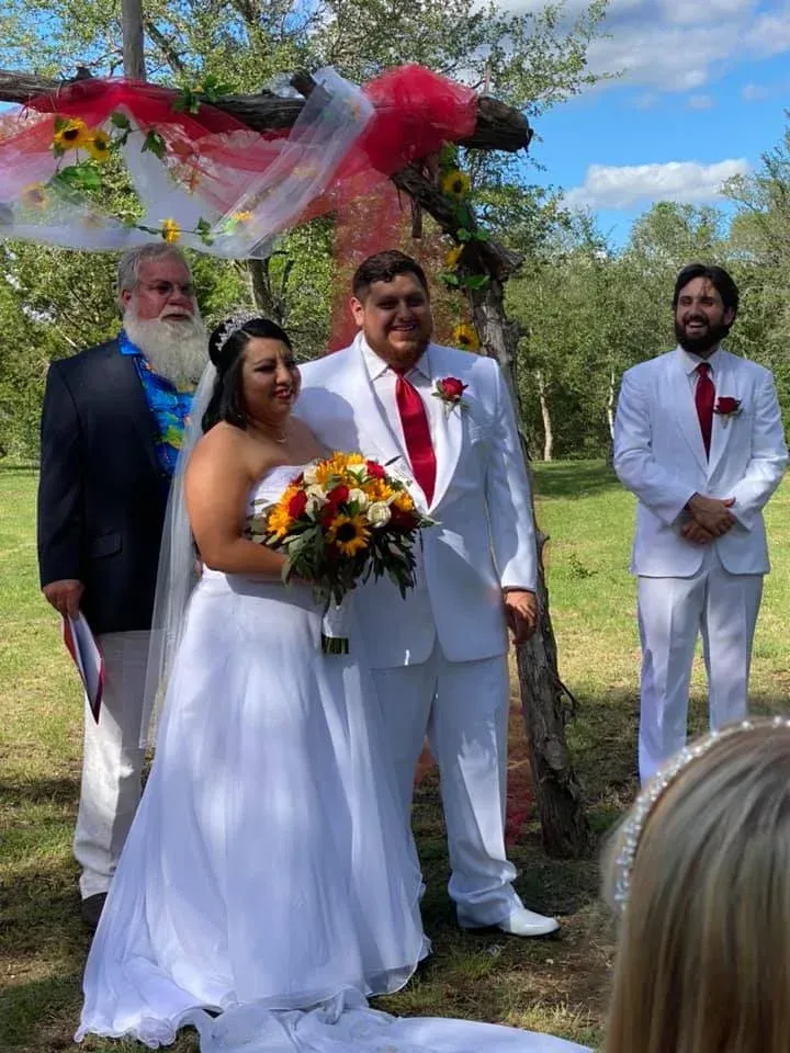 A bride and groom are posing for a picture at their wedding ceremony.