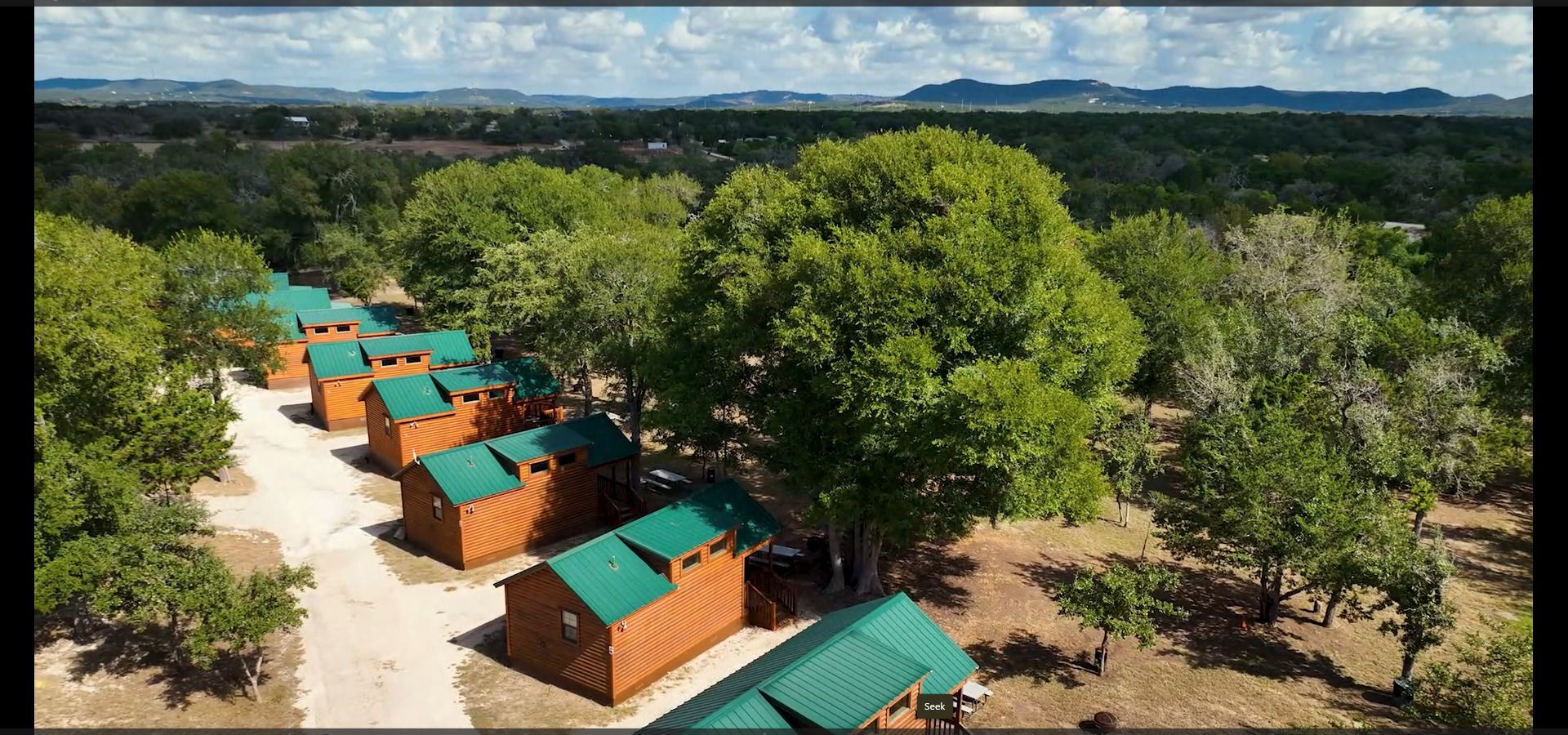 An aerial view of a row of wooden cabins surrounded by trees.