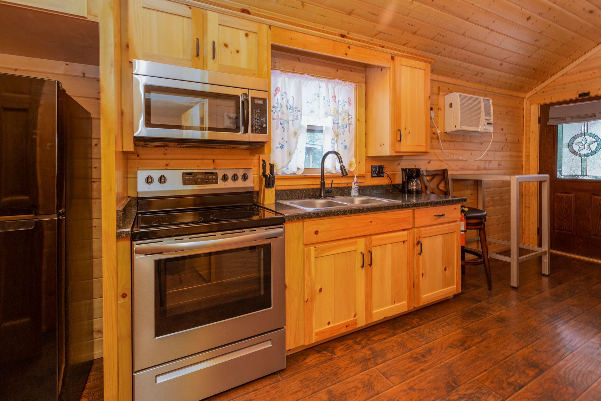 A kitchen in a log cabin with stainless steel appliances and wooden cabinets.