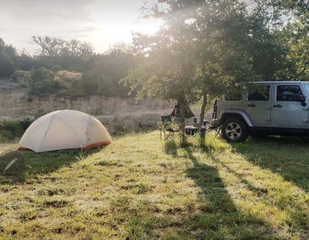 A tent and a jeep are parked in a grassy field.
