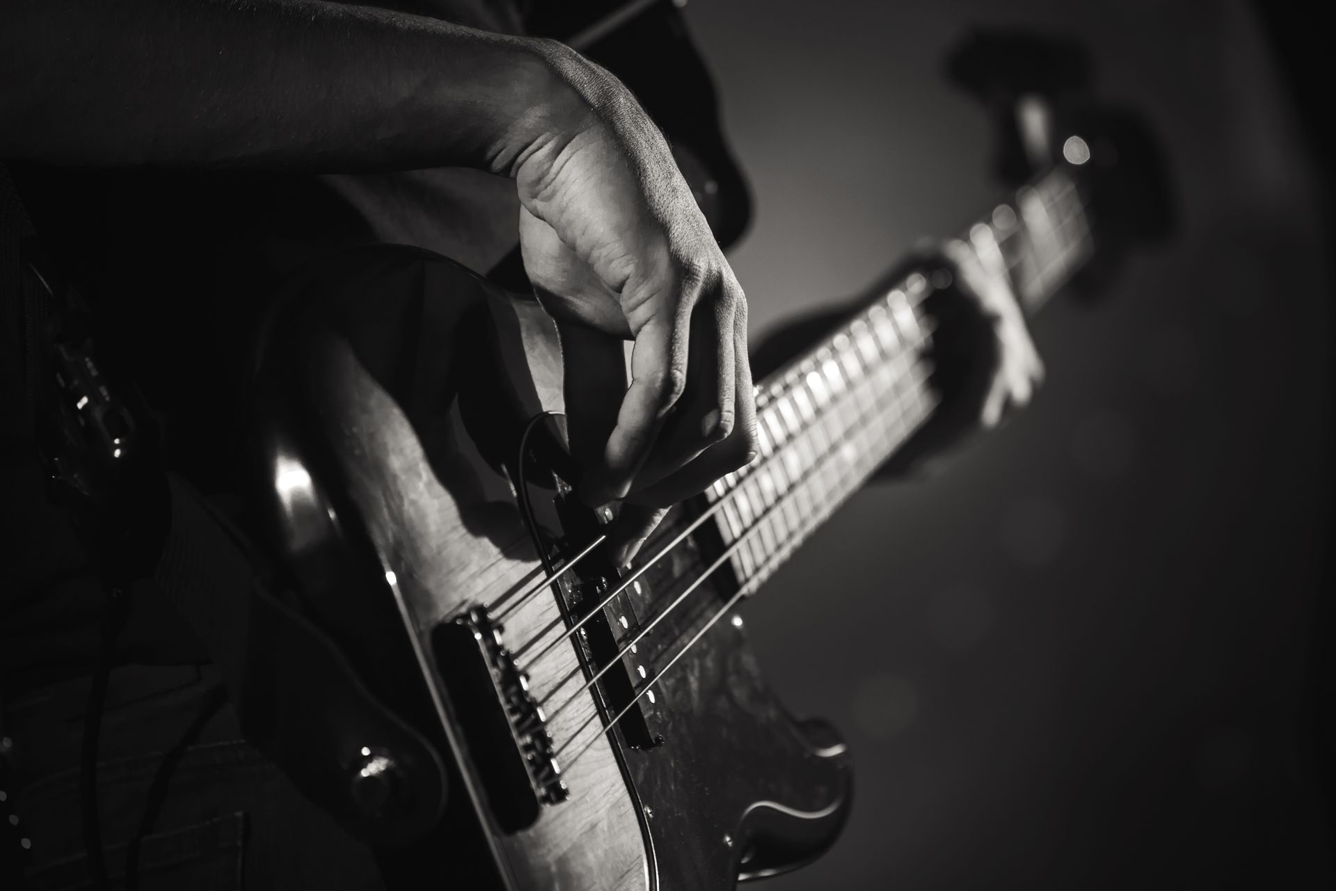 A black and white photo of a person playing a bass guitar