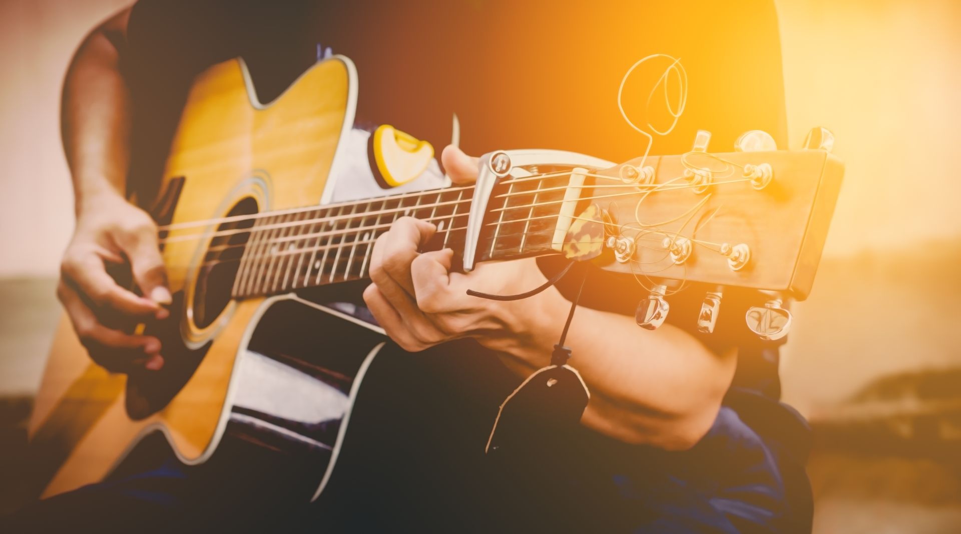 A man is playing an acoustic guitar while sitting down.