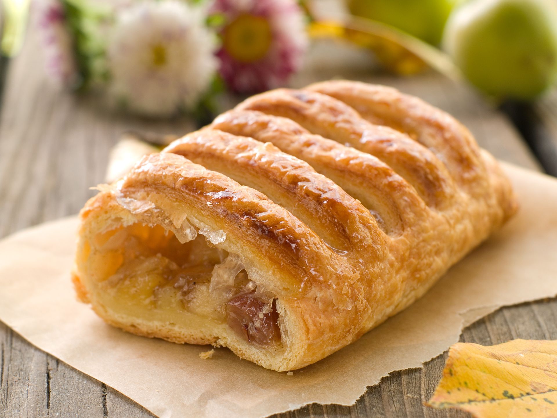 A pastry is sitting on a piece of paper on a wooden table.
