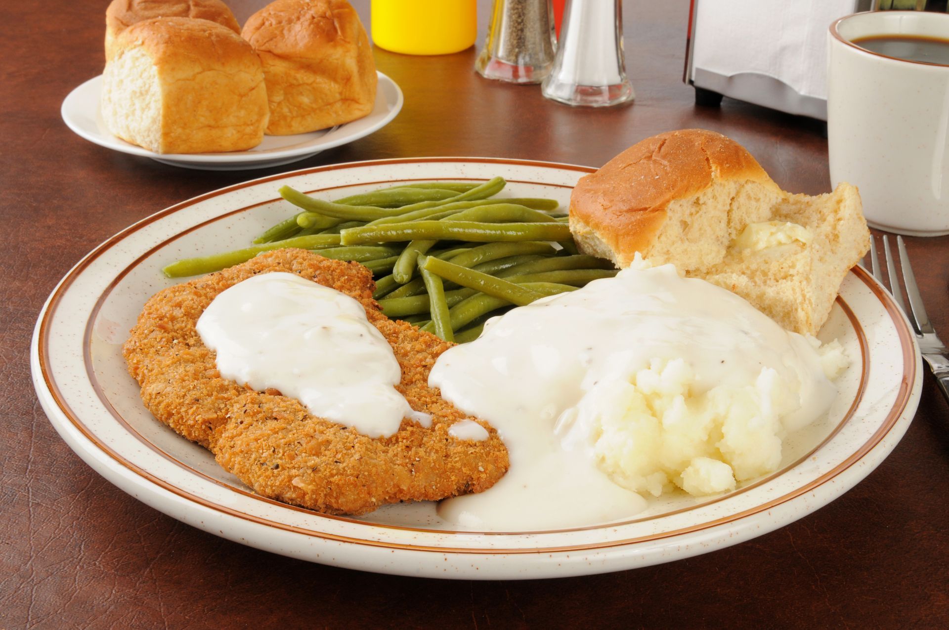 A plate of chicken fried steak mashed potatoes green beans and gravy