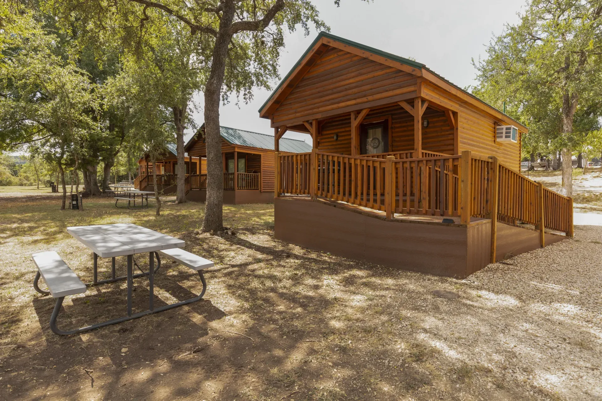 A wooden cabin with a ramp and a picnic table in front of it.