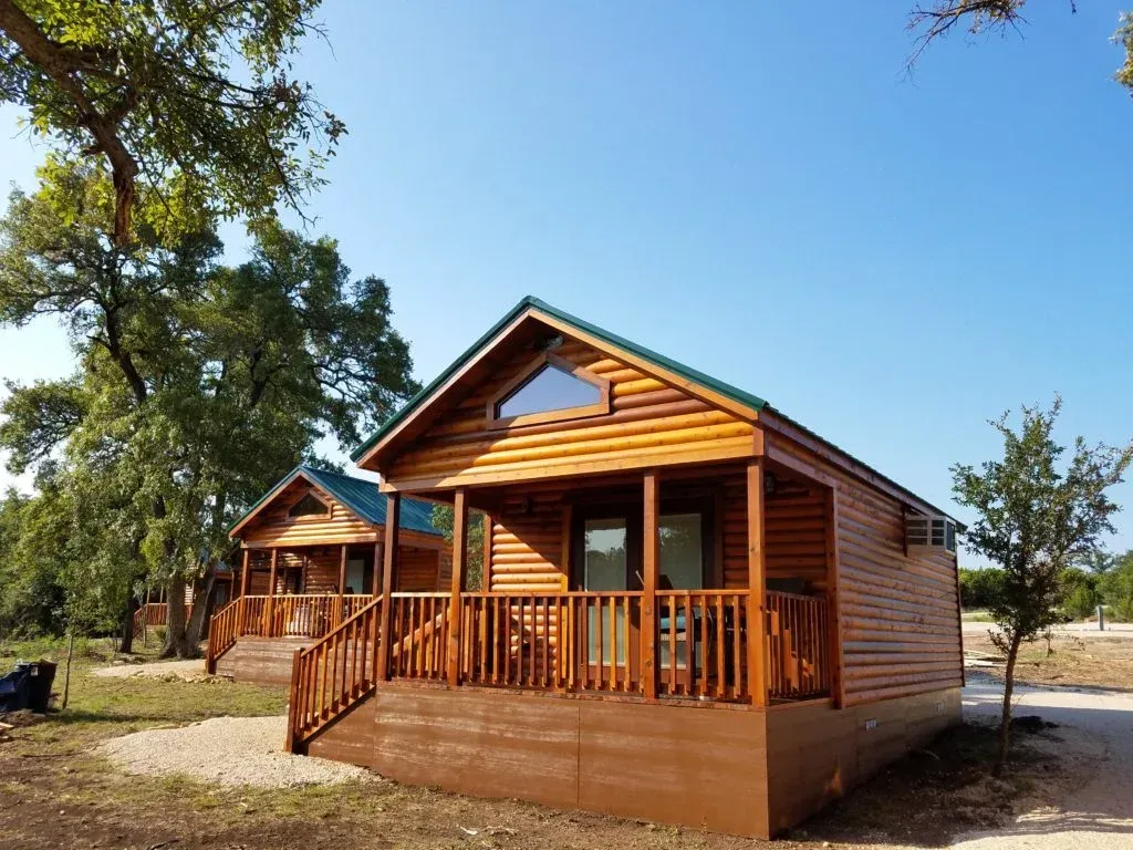 A small wooden cabin with a large porch and stairs.