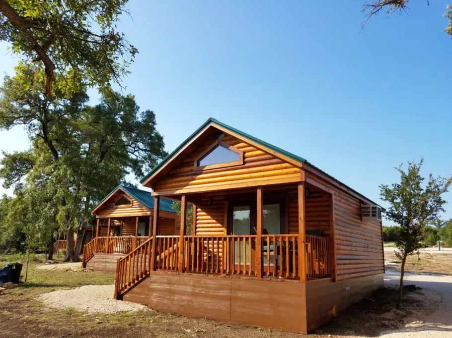 A small wooden cabin with a large porch and stairs.