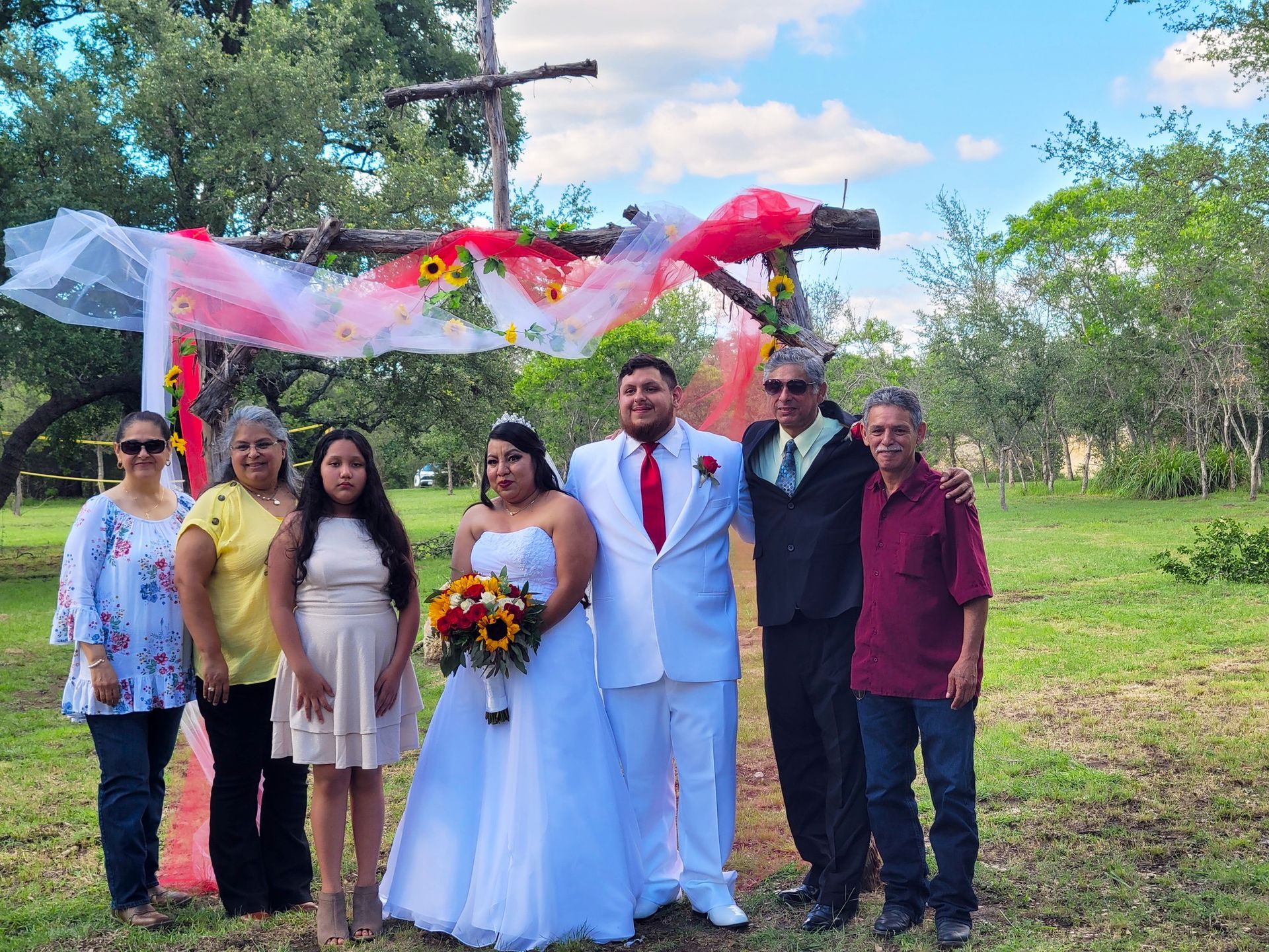 A bride and groom are posing for a picture with their family.