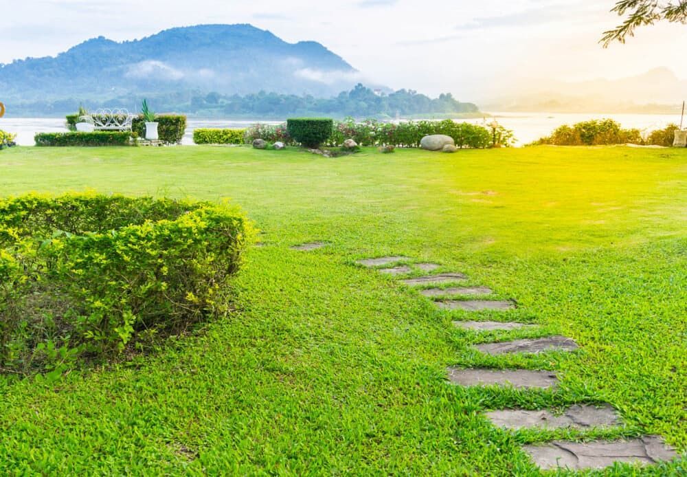 A Stone Path Leading Through A Lush Green Field With Mountains — Paxi Homes Brad Clarke in Port Macquarie, NSW