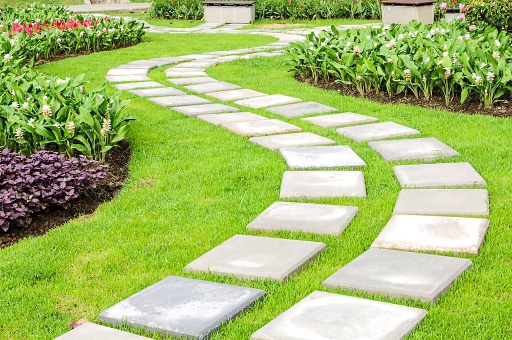 A Stone Walkway In A Garden Surrounded By Grass And Flowers — Paxi Homes Brad Clarke in Port Macquarie, NSW