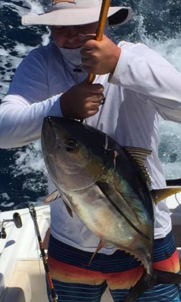 A man is holding a large fish on a boat.