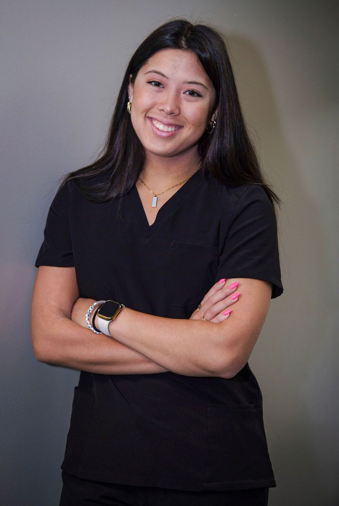 A woman in a black scrub top is smiling for the camera.