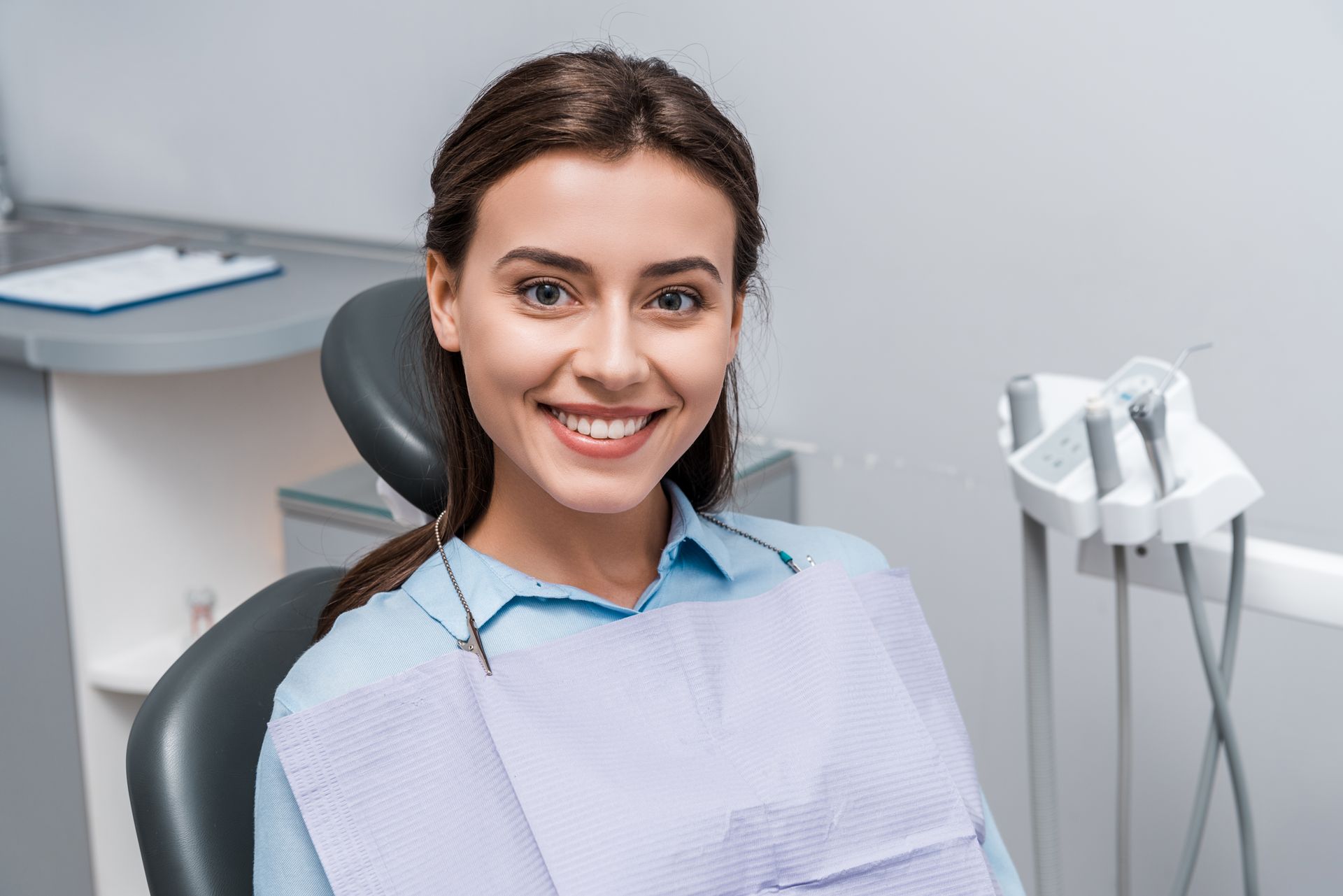 A woman is sitting in a dental chair and smiling.
