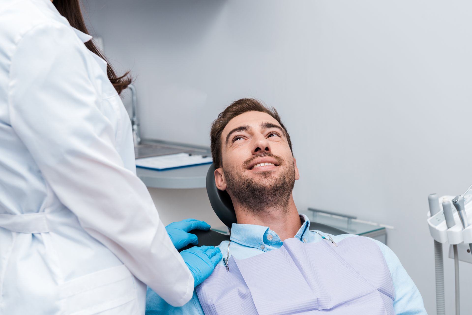 A man is sitting in a dental chair with a dentist standing next to him.
