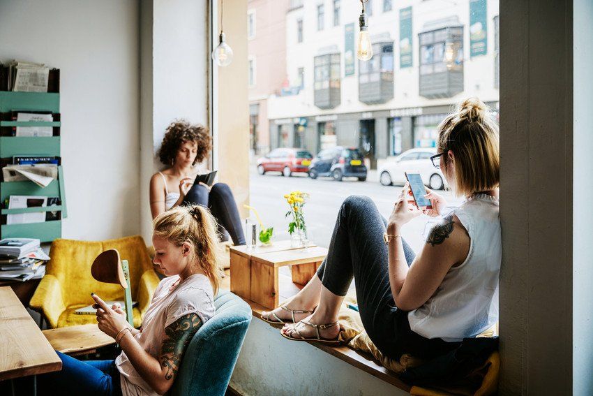 women in cafe using phones