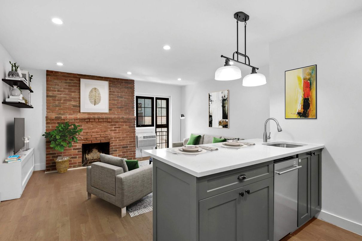 An empty kitchen with a large island and a brick fireplace.