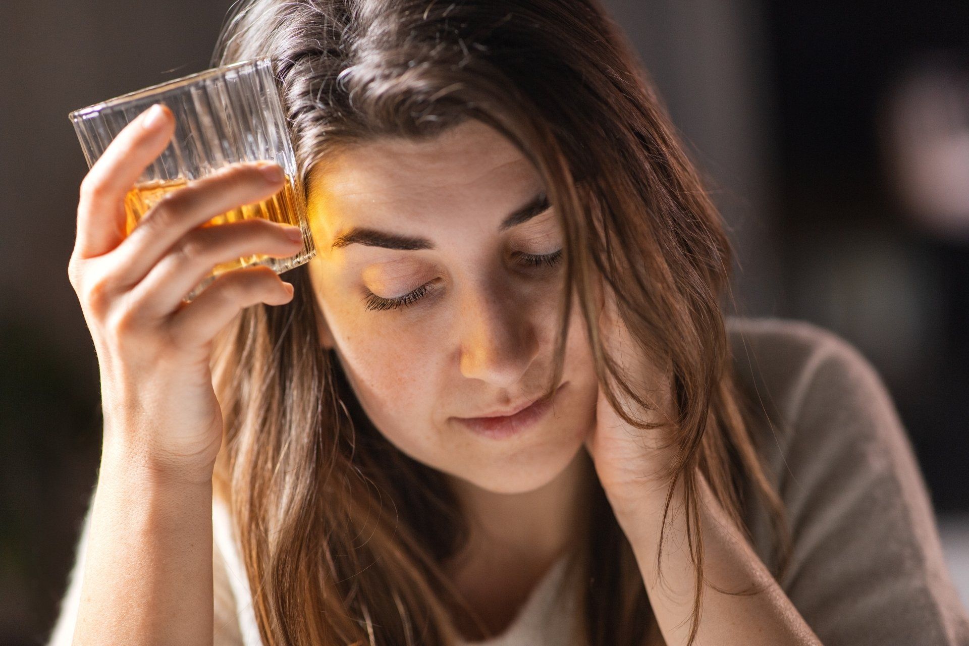 A woman is holding a glass of whiskey in her hand.