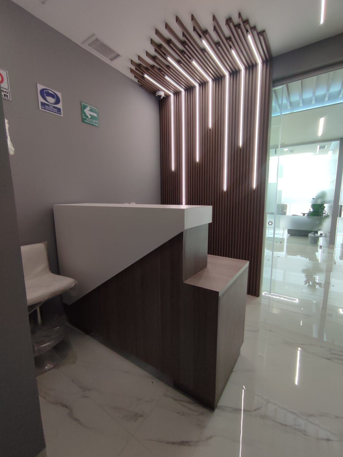 Una sala de espera con una escalera que conduce a un mostrador de recepción.