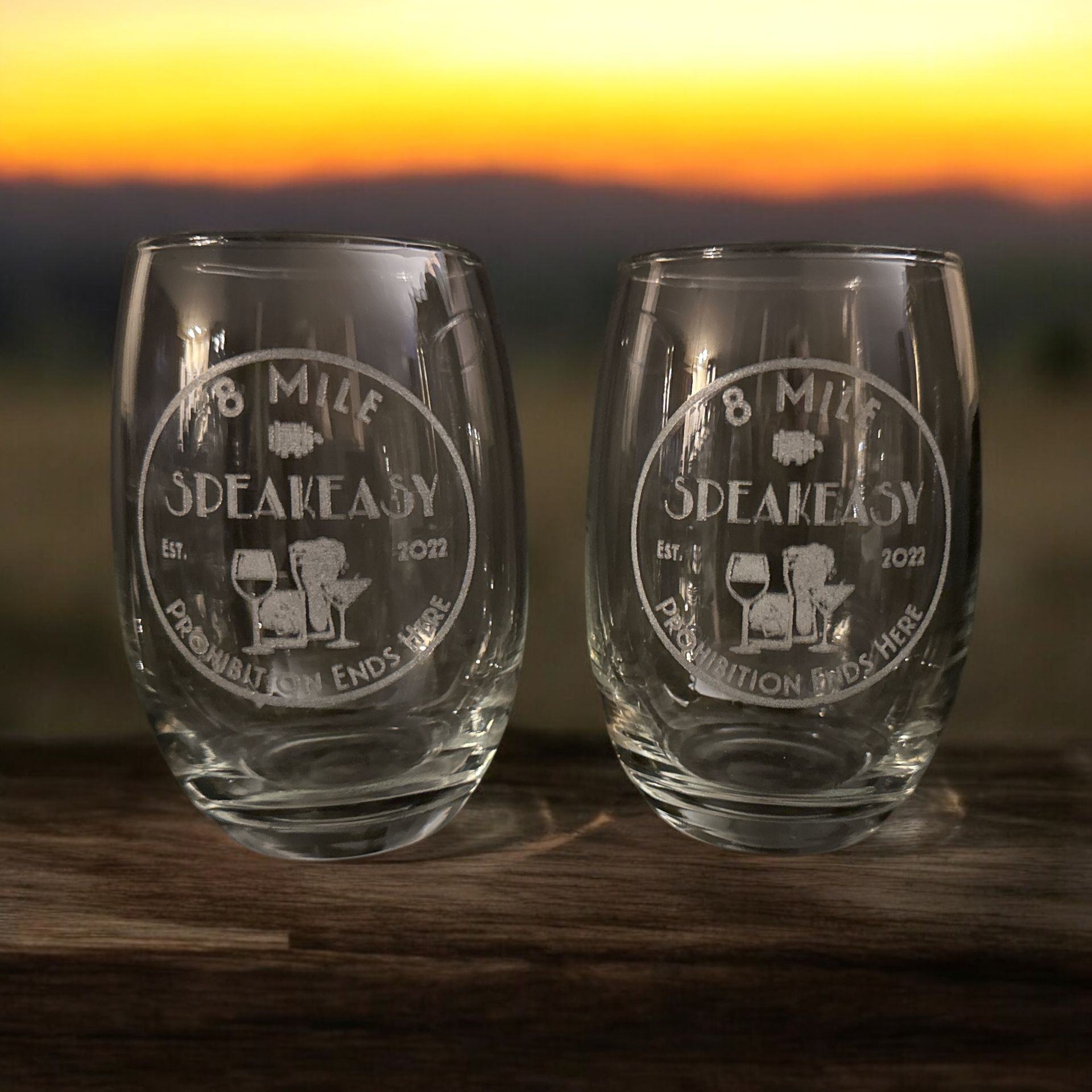 Two wine glasses are sitting on a wooden table.