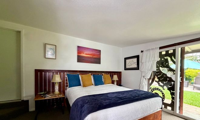 Bright bedroom with a bed, lamps, wall art, and a sliding glass door to a patio.
