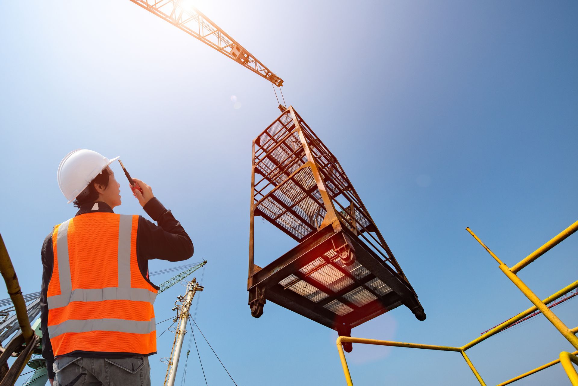 A man in an orange vest on a construction site showcases certified crane operation in Fairfield Coun