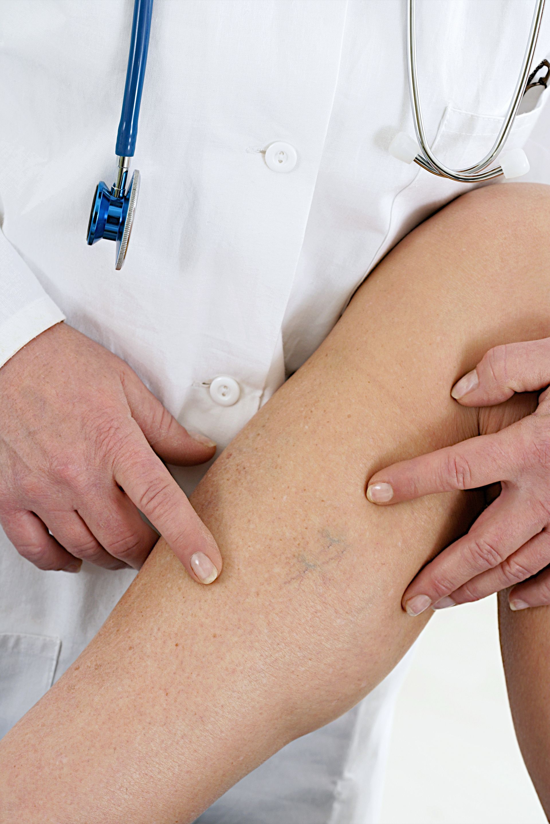 A doctor examines a patient 's leg with a stethoscope around his neck