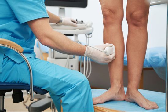 A doctor is examining a patient 's legs with an ultrasound
