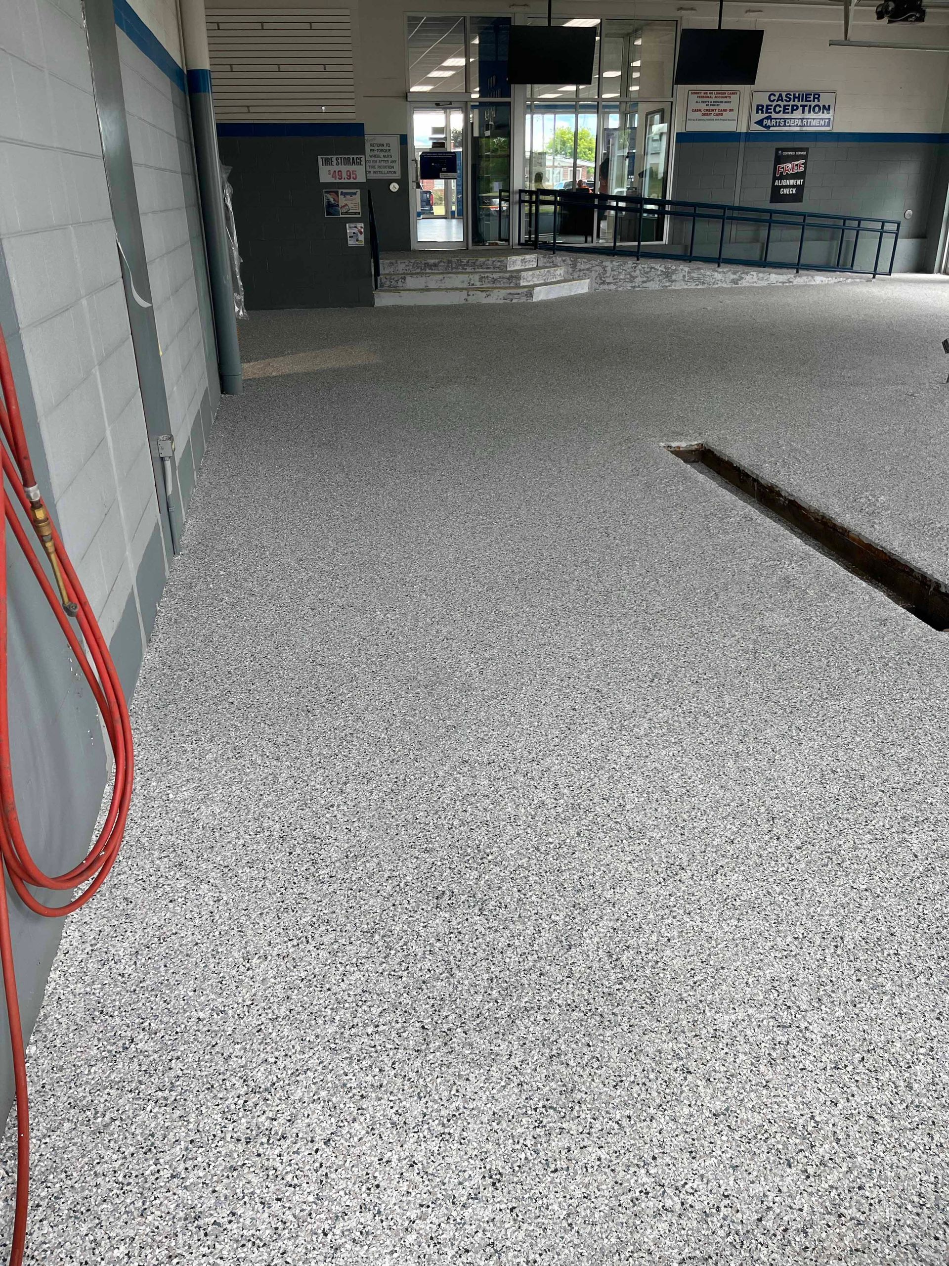 A large room with a concrete floor and a red hose.