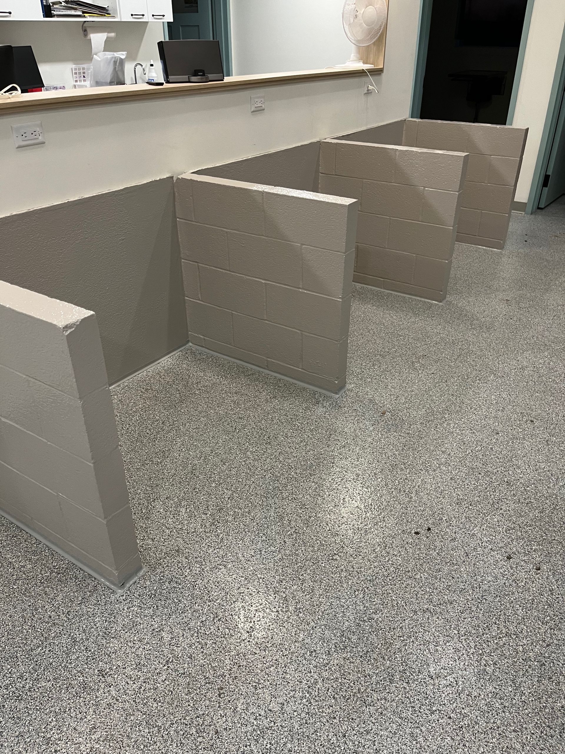 A row of cubicles in a room with a marble floor.