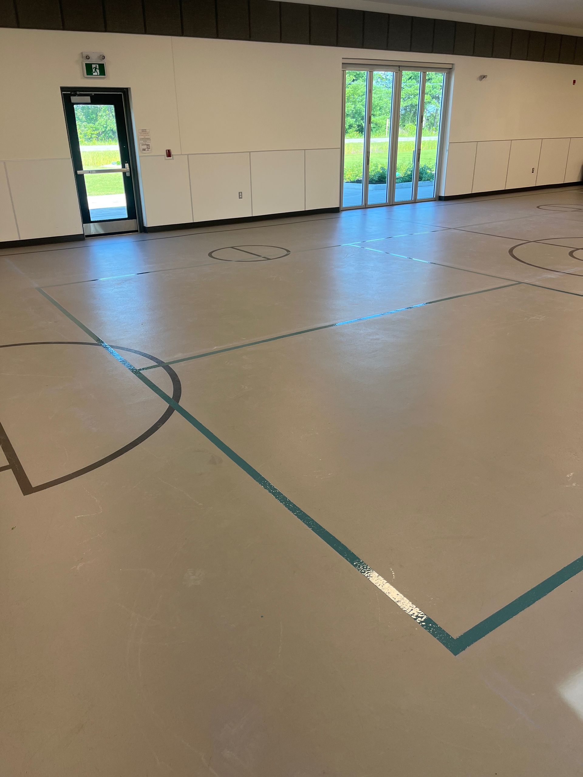 A large empty room with a basketball court and a door.
